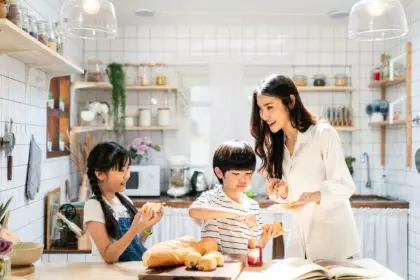 Asian mother and children standing at cooking counter that food ingredient put on table.