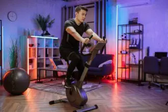 Home fitness workout, young asian man athlete training on smart stationary bike indoors
