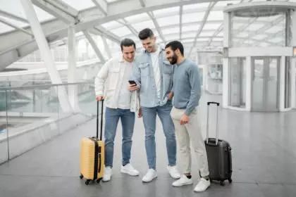 Three Tourists Men Using Smartphones Using Travel Application At Airport